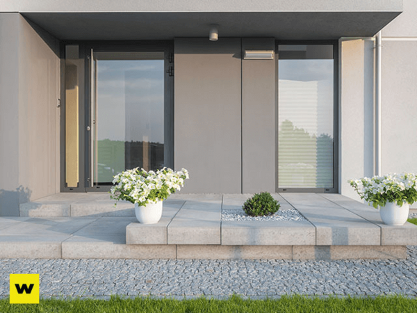 Moderner Hauseingang mit großen Glasflächen, Pflanzkübeln und gepflegtem Eingangsbereich.