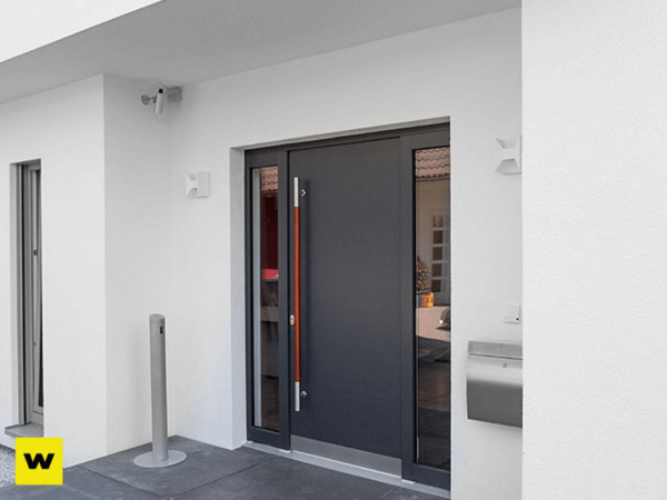 Moderne Haustür aus Aluminium mit Seitenteil, Briefkasten und Überwachungskamera am Haus.